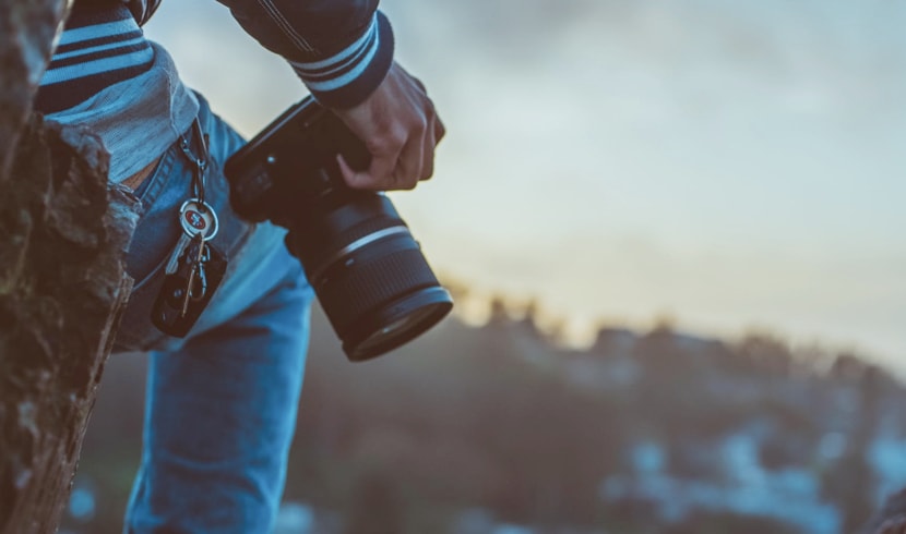 Silhouette of a man on top of rocks with a camera resting on his right knee