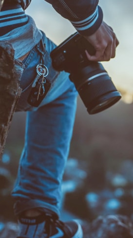 Silhouette of a man on top of rocks with a camera resting on his right knee